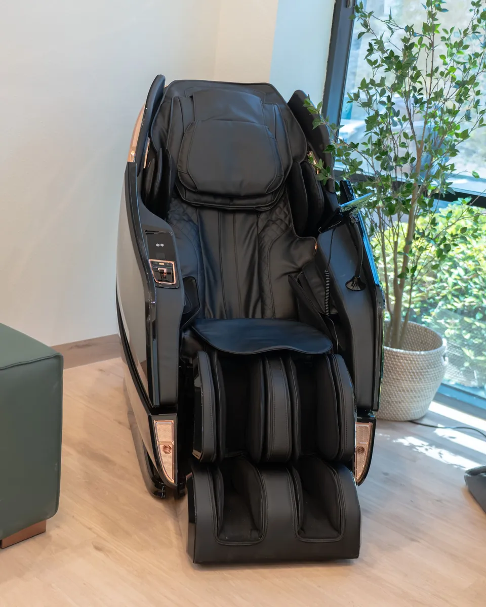 Full-body massage chair beside a window in the group IV lounge
