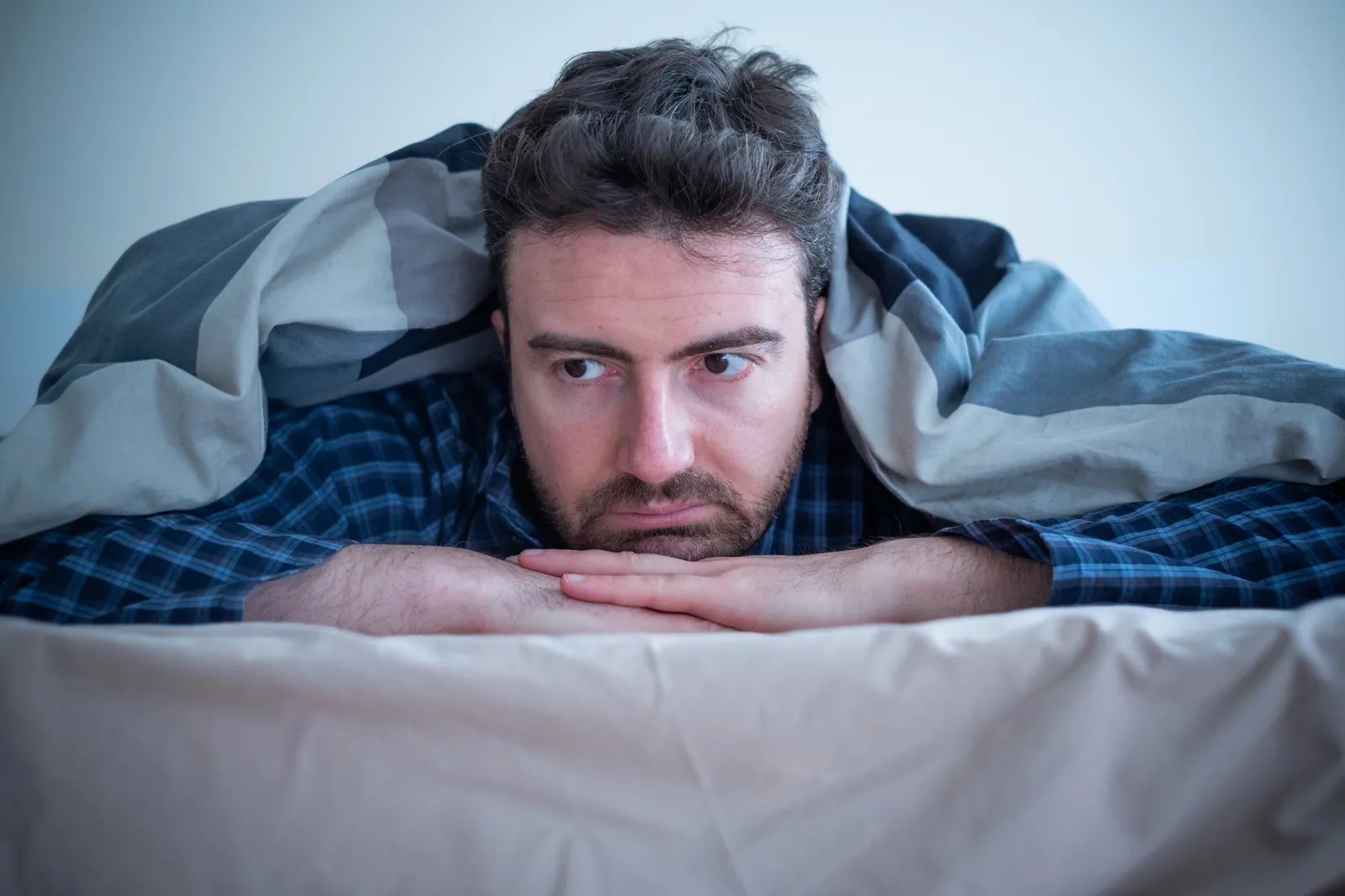 Man peeking out from under a blanket on a slow morning